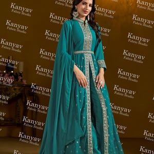 Pode incluir: Conjunto formal turquesa com bordados prateados, composto por um casaco comprido aberto, cal&ccedil;as e um len&ccedil;o. O casaco tem gola alta e cintura cintada. O fundo apresenta o texto "Kanyav Fabric Studio".