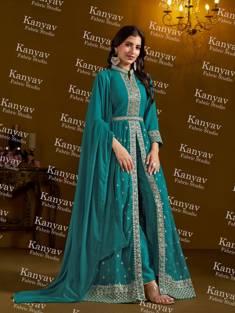 Pode incluir: Conjunto formal turquesa com bordados prateados, composto por um casaco comprido aberto, cal&ccedil;as e um len&ccedil;o. O casaco tem gola alta e cintura cintada. O fundo apresenta o texto "Kanyav Fabric Studio".