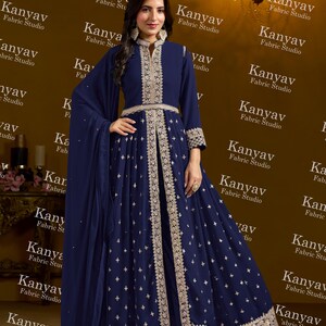 Pode incluir: Um vestido de noite azul marinho com intrincados bordados dourados. O vestido apresenta uma gola alta, mangas compridas e uma saia fluida. O design inclui padr&otilde;es e enfeites delicados, criando um look elegante e sofisticado.