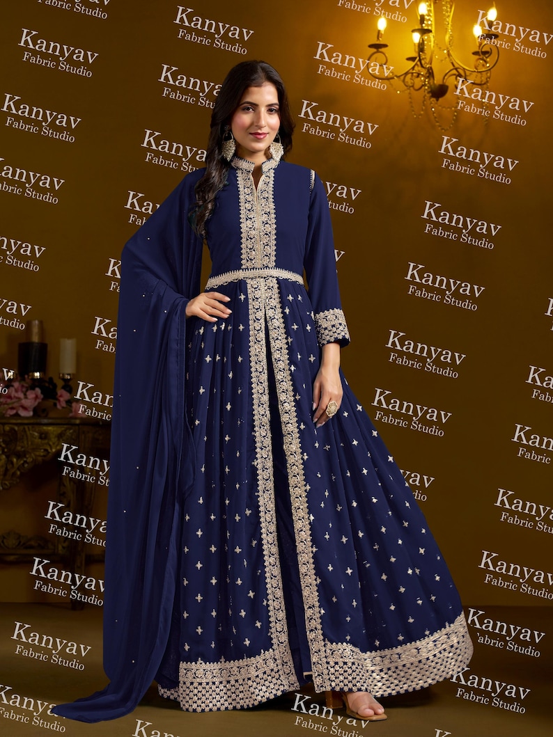Pode incluir: Um vestido de noite azul marinho com intrincados bordados dourados. O vestido apresenta uma gola alta, mangas compridas e uma saia fluida. O design inclui padr&otilde;es e enfeites delicados, criando um look elegante e sofisticado.