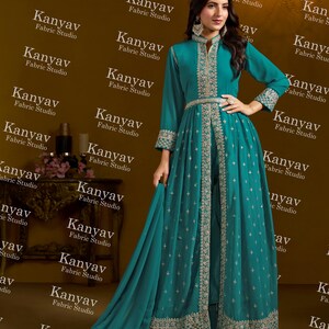Pode incluir: Um vestido formal turquesa com bordados prateados intrincados. O vestido apresenta mangas compridas, gola alta e uma saia fluida com cauda. O vestido &eacute; da Kanyav Fabric Studio.