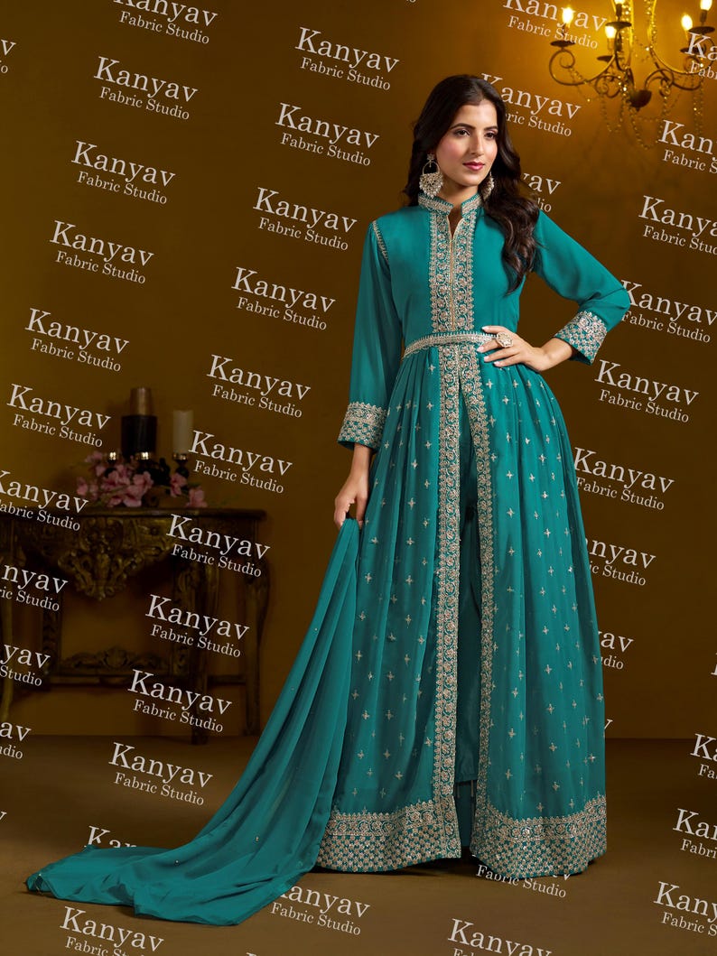 Pode incluir: Um vestido formal turquesa com bordados prateados intrincados. O vestido apresenta mangas compridas, gola alta e uma saia fluida com cauda. O vestido &eacute; da Kanyav Fabric Studio.
