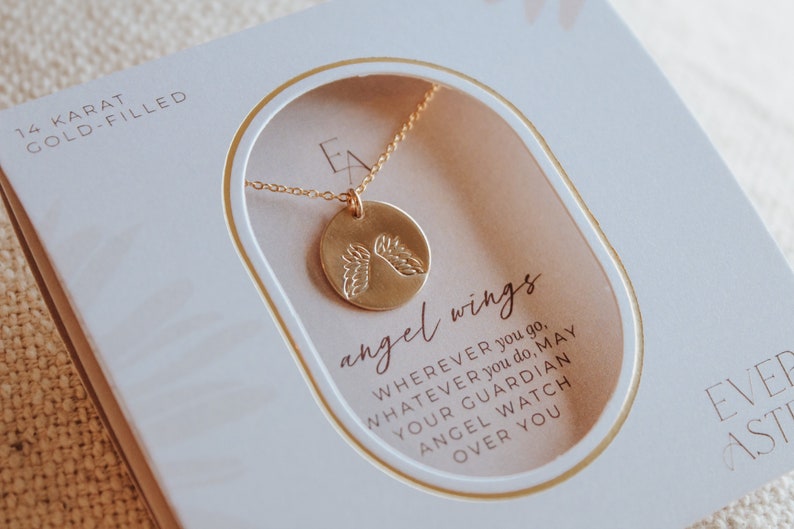Puede incluir: Un collar de oro relleno con un colgante redondo que presenta un par de alas de &aacute;ngel. El collar viene en una caja blanca con el texto "angel wings" y "WHEREVER you go, WHATEVER you do, MAY YOUR GUARDIAN ANGEL WATCH OVER YOU".