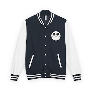 Puede incluir: Una chaqueta estilo universitario azul marino con mangas blancas, que presenta un gráfico circular blanco con dos ojos negros y una boca dentada en el pecho izquierdo. La chaqueta tiene cuello, puños y dobladillo acanalados con rayas blancas.