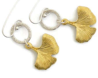 May include: A pair of gold ginkgo leaf earrings with silver hoops and a textured finish.