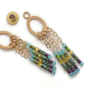 May include: Gold dangle earrings with a chain and green, blue, and purple beads.