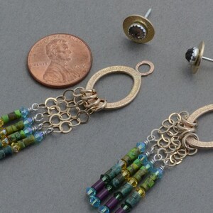 May include: A pair of gold dangle earrings with a chain and a variety of colorful beads. The earrings are about the size of a US penny.
