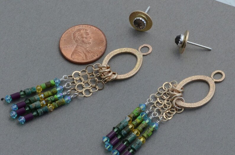 May include: A pair of gold dangle earrings with a chain and a variety of colorful beads. The earrings are about the size of a US penny.