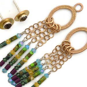 May include: A pair of gold oval earrings with a dangling chain and colorful beads. The beads are in shades of green, blue, purple, and yellow.