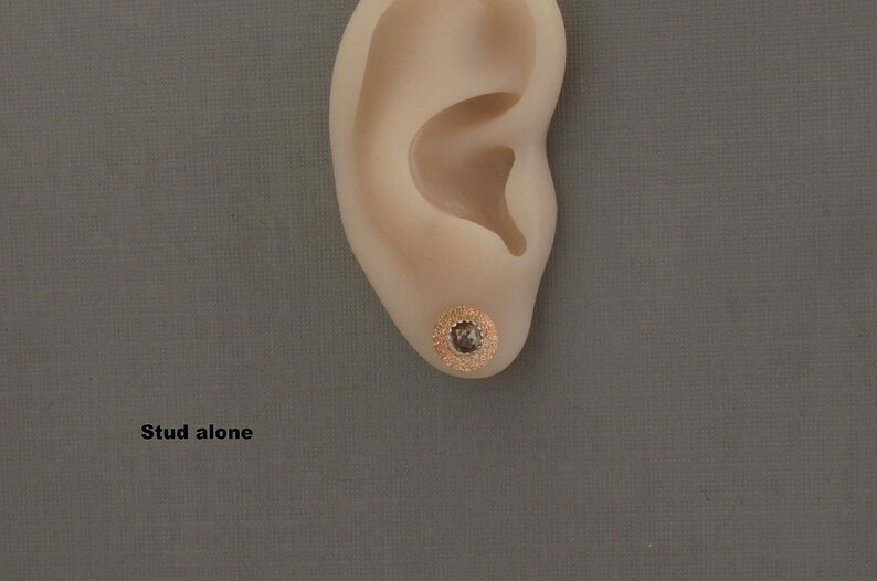 May include: A close-up of a gold stud earring with a small, clear gemstone in the center. The earring is worn in a person's earlobe. The text "Stud alone" is visible below the ear.