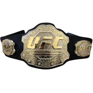 May include: A championship belt with a large gold-colored central plate featuring the letters "UFC" and the words "Ultimate Fighting Championship." The belt has a black strap and two smaller side plates with the "UFC" logo.