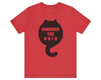 May include: Red t-shirt with a black cat-shaped graphic that says "EMBRACE THE VOID." The graphic is a stylized cat silhouette with the text inside the body of the cat. The shirt is made of a soft material.