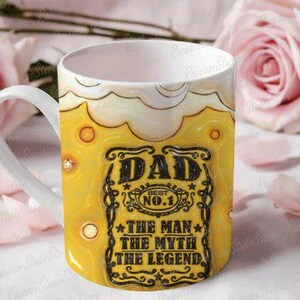 May include: A white ceramic mug with a yellow and brown design. The mug features the text "DAD BEST NO. 1 THE MAN THE MYTH THE LEGEND" in black. The mug is decorated with a beer-like design.
