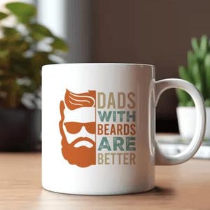 May include: White ceramic mug with a handle. The mug features a graphic of a bearded man with sunglasses in shades of orange and brown. Text on the mug reads "DADS WITH BEARDS ARE BETTER" in a mix of colors.
