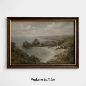 Puede incluir: Una pintura de paisaje enmarcada que representa una escena costera con acantilados rocosos, una playa de arena y el océano bajo un cielo nublado. La obra de arte está en un marco de madera oscura con un borde interior dorado. El texto "Madame Art Prints" está en la parte inferior.
