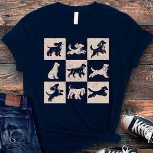 May include: Navy blue t-shirt featuring a grid of nine dog illustrations in various poses. The dogs are in a vintage style, with a distressed beige background. The shirt is paired with blue jeans and black sneakers.