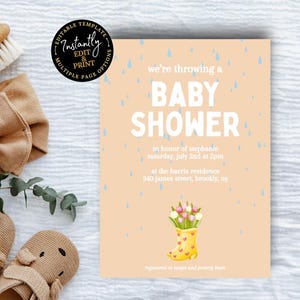 May include: A baby shower invitation with the text "BABY SHOWER" on a peach background, featuring a yellow rain boot with flowers. The image also includes a tan headband, baby shoes, and a wooden brush.