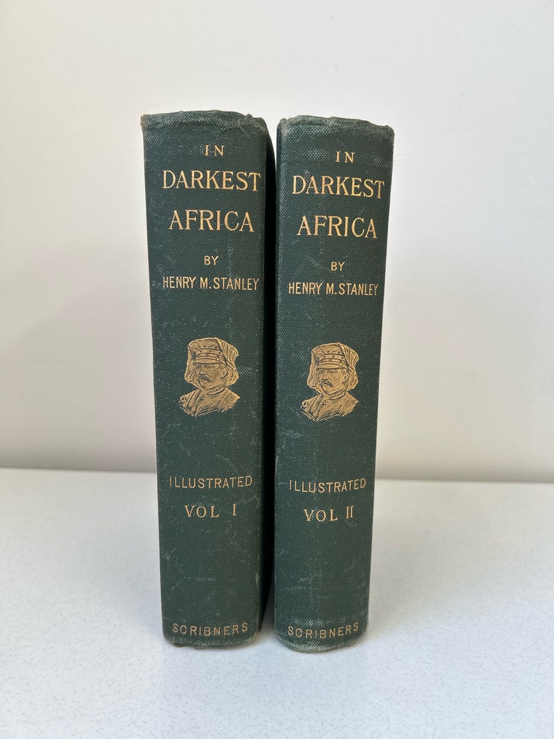 May include: Two vintage books titled "In Darkest Africa" by Henry M. Stanley. The green hardcovers feature gold lettering and illustrations. Volume I and Volume II are displayed side by side, published by Scribners.