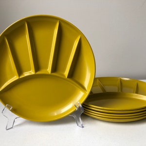May include: Set of six mustard yellow divided plates. Each plate has a unique fan-shaped design with five compartments. The plates are made of a durable material and are ideal for serving appetizers or snacks.