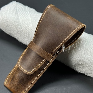 May include: A brown leather case with a stitched edge for a safety razor.
