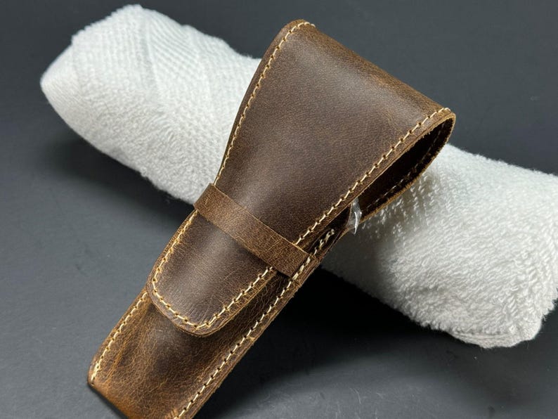 May include: A brown leather case with a stitched edge for a safety razor.