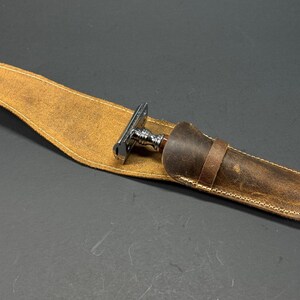 May include: A brown leather case with a stitched edge and a silver and wood safety razor inside.
