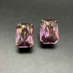 May include: A pair of purple gemstone earrings with gold settings. The gemstones are cut in a rectangular shape with facets.