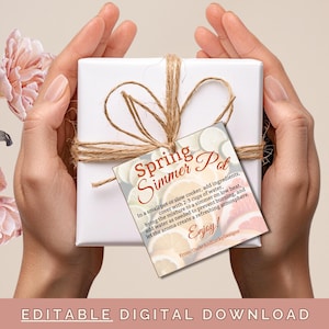 Peut inclure: Une boîte cadeau blanche attachée avec de la ficelle et une étiquette cadeau qui indique "Spring Simmer Pot" avec des instructions pour faire un pot mijoté. L'étiquette cadeau a un motif floral avec des fleurs roses et orange.