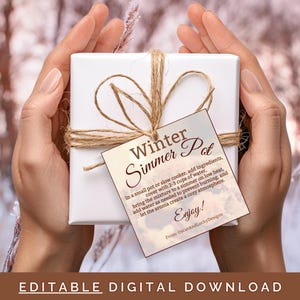 May include: A printable gift tag with a brown background and white text that reads "Winter Simmer Pot". The tag is tied with twine and is being held by a hand in front of a snowy background.