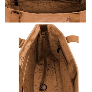 K&ouml;nnte beinhalten: Eine braune Ledertasche mit Sternendesign und einer Rei&szlig;verschlusstasche. Das Innere der Tasche ist mit einem Konstellationsdruck ausgekleidet.