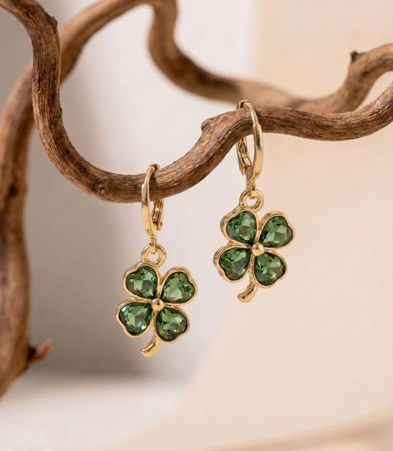Peut inclure: Une paire de boucles d'oreilles cr&eacute;oles dor&eacute;es avec des pendentifs en forme de tr&egrave;fle &agrave; quatre feuilles. Chaque tr&egrave;fle est compos&eacute; de quatre p&eacute;tales en cristal vert fonc&eacute; facett&eacute;, sertis dans une monture en m&eacute;tal dor&eacute; poli.