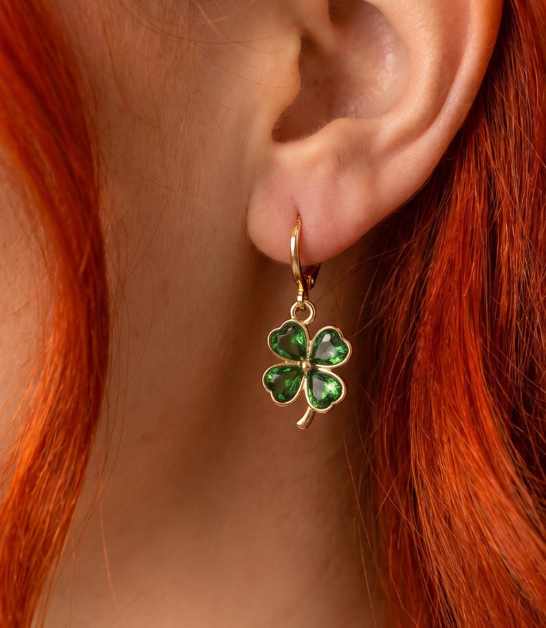 Peut inclure: Une boucle d'oreille cr&eacute;ole dor&eacute;e orn&eacute;e d'un pendentif en forme de tr&egrave;fle &agrave; quatre feuilles. Le pendentif est compos&eacute; d'un contour en m&eacute;tal dor&eacute; poli et rempli d'&eacute;mail vert translucide, offrant une finition brillante et lumineuse.