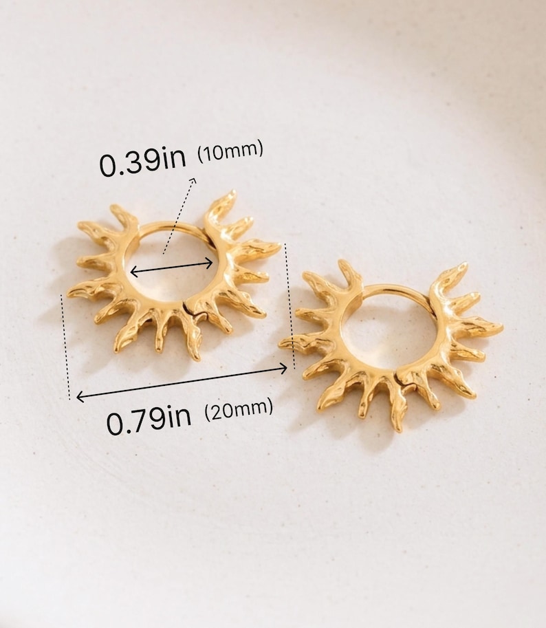 Op de afbeelding: Een paar goudkleurige oorringen met een zonnestraalontwerp. De binnendiameter is 10 mm en de totale buitendiameter is 20 mm. De oorbellen hebben getextureerde, onregelmatige stralen die uitsteken vanaf het ronde frame van de ring.