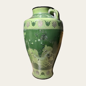 May include: A green ceramic vase with a handle and a gold and green design. The vase features a scene of a chariot race with horses and riders.