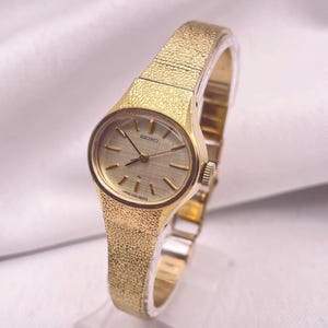 Vintage 1970s Seiko Gold Plated Oval Case Gold Linen Dial Ladies 17 Jewel Wind Up Wristwatch With Gold "Pebble" Style Bracelet Strap