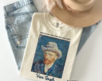 Może przedstawiać: Koszulka w kolorze kości słoniowej z nadrukiem autoportretu Vincenta van Gogha w szarym filcowym kapeluszu. Na koszulce nadrukowany jest tekst "Self Portrait with Grey Felt Hat (1887)" i "Van Gogh".