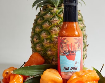 Könnte beinhalten: Eine Flasche Culture Hot Sauce mit der Aufschrift "The Don", mit einer Ananas, Habanero-Paprika und Sichuanpfefferkörnern.