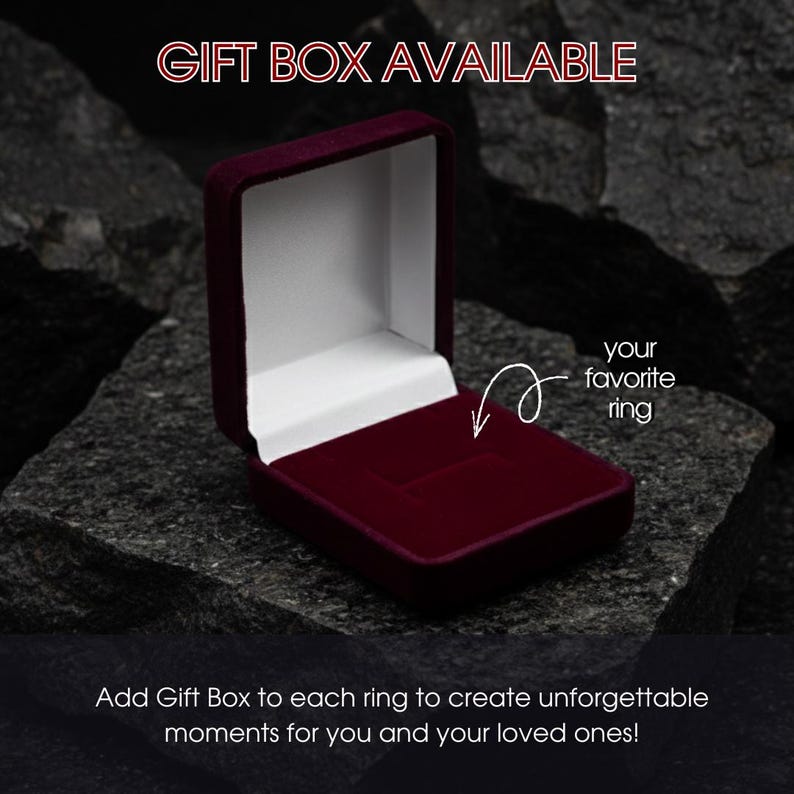 Op de afbeelding: Een open, bordeauxrode fluwelen ringdoos, ideaal om een ring te presenteren. De doos staat tegen een donkere, getextureerde achtergrond. Tekst luidt "GIFT BOX AVAILABLE" en "your favorite ring". De tekst onderaan luidt "Add Gift Box to each ring to create unforgettable moments for you and your loved ones!"