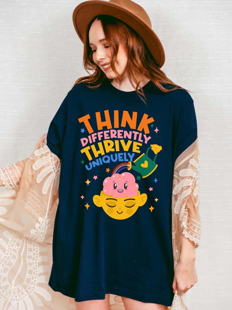 Autism Shirt with a positive message: 'Think Differently, Thrive Uniquely.' This Autism Awareness Shirt features a colorful design with a smiling brain, rainbow, and watering can, symbolizing growth and neurodiversity. Perfect as an Autism Teacher Shirt, Neurodivergent Shirt, ADHD Shirt, Anxiety Shirt, or ABA Therapist Shirt to promote inclusivity and self-expression