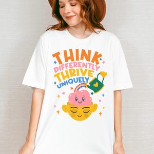 Autism Shirt with a positive message: 'Think Differently, Thrive Uniquely.' This Autism Awareness Shirt features a colorful design with a smiling brain, rainbow, and watering can, symbolizing growth and neurodiversity. Perfect as an Autism Teacher Shirt, Neurodivergent Shirt, ADHD Shirt, Anxiety Shirt, or ABA Therapist Shirt to promote inclusivity and self-expression