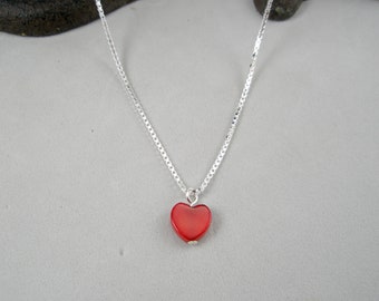 May include: A silver chain necklace with a red heart pendant.
