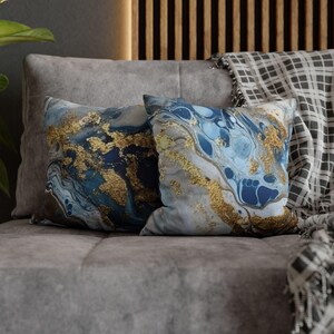 May include: Two decorative throw pillows with a blue, white, and gold marble pattern. The pillows are on a gray couch.