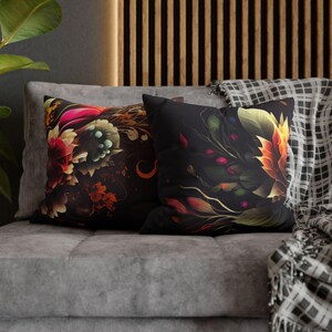 May include: Two decorative throw pillows with floral patterns. The pillow on the left has a dark background with colorful flowers and swirls. The pillow on the right has a black background with a single large flower in shades of orange and yellow.