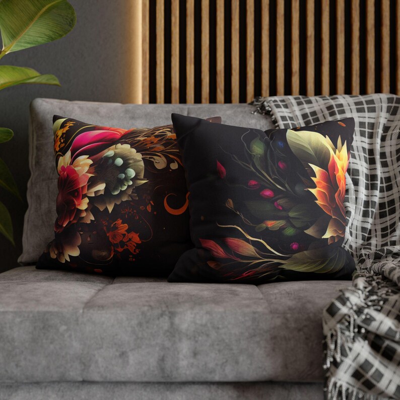 May include: Two decorative throw pillows with floral patterns. The pillow on the left has a dark background with colorful flowers and swirls. The pillow on the right has a black background with a single large flower in shades of orange and yellow.