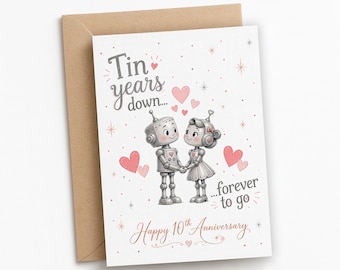 May include: A white greeting card with a brown envelope featuring two illustrated robots holding hands. The text reads Tin years down... forever to go and Happy 10th Anniversary. The design includes pink hearts and small star accents.