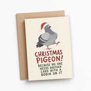 May include: A greeting card with a cream background featuring a gray pigeon wearing a red and white Santa hat. The text reads: CHRISTMAS PIGEON! BECAUSE NO ONE NEEDS ANOTHER CARD WITH A ROBIN ON IT. The card is paired with a brown kraft envelope.