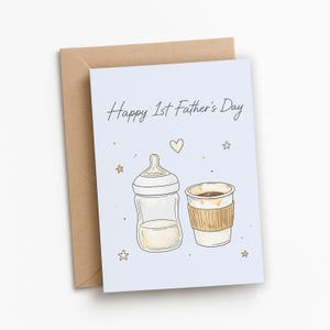 Op de afbeelding: Lichtblauwe kaart met de tekst "Happy 1st Father's Day" met illustraties van een babyfles en een koffiekopje. De kaart wordt vergezeld door een bruine envelop en versierd met kleine gouden sterren en een hart.