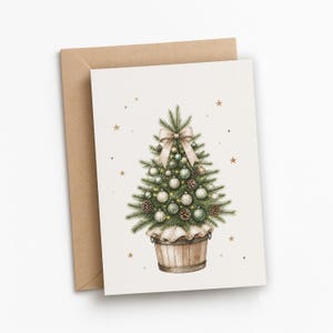 May include: A greeting card featuring a watercolor illustration of a potted Christmas tree in a wooden bucket. The tree is decorated with light-colored ornaments, pinecones, and a large beige bow at the top, surrounded by small gold stars.