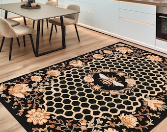 May include: Black and beige area rug with a honeycomb pattern and floral accents. A stylized bee is in the center of the honeycomb.