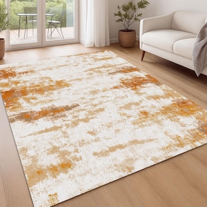 May include: A rectangular area rug with an abstract design. The rug features a white background with brushstroke-like patterns in shades of orange, tan, and brown. The rug is placed on a hardwood floor in a living room setting.